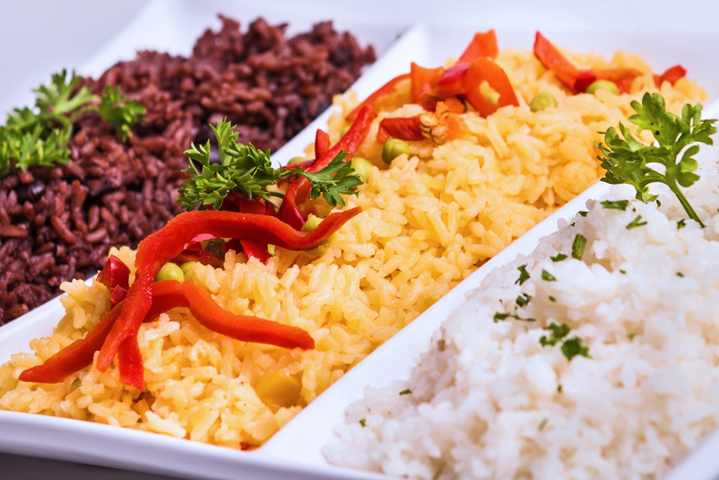 Congrí, yellow rice with red peppers and peas, and white rice on a divided platter