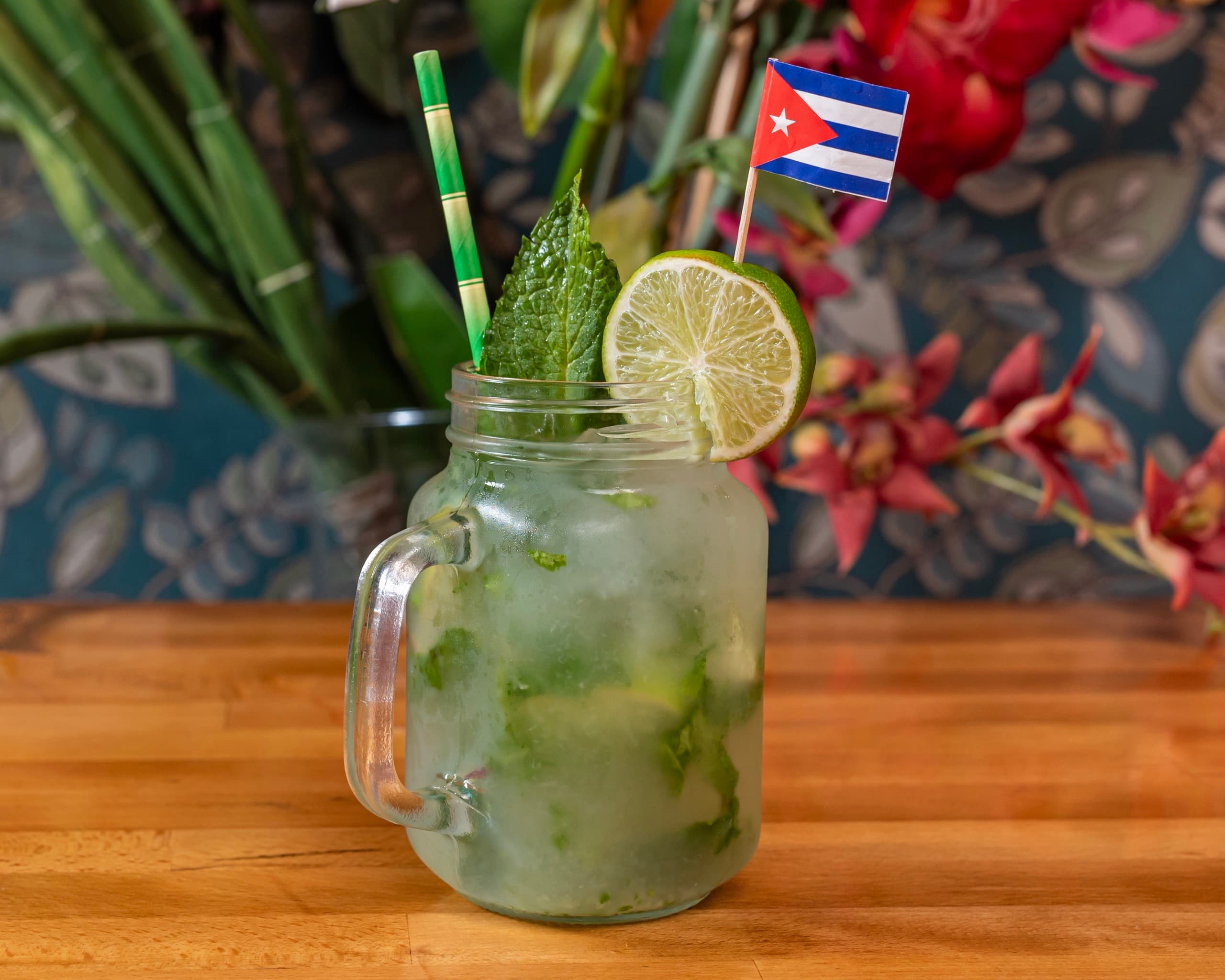 A mojito in a mason jar with fresh mint, lime and a small Cuban flag