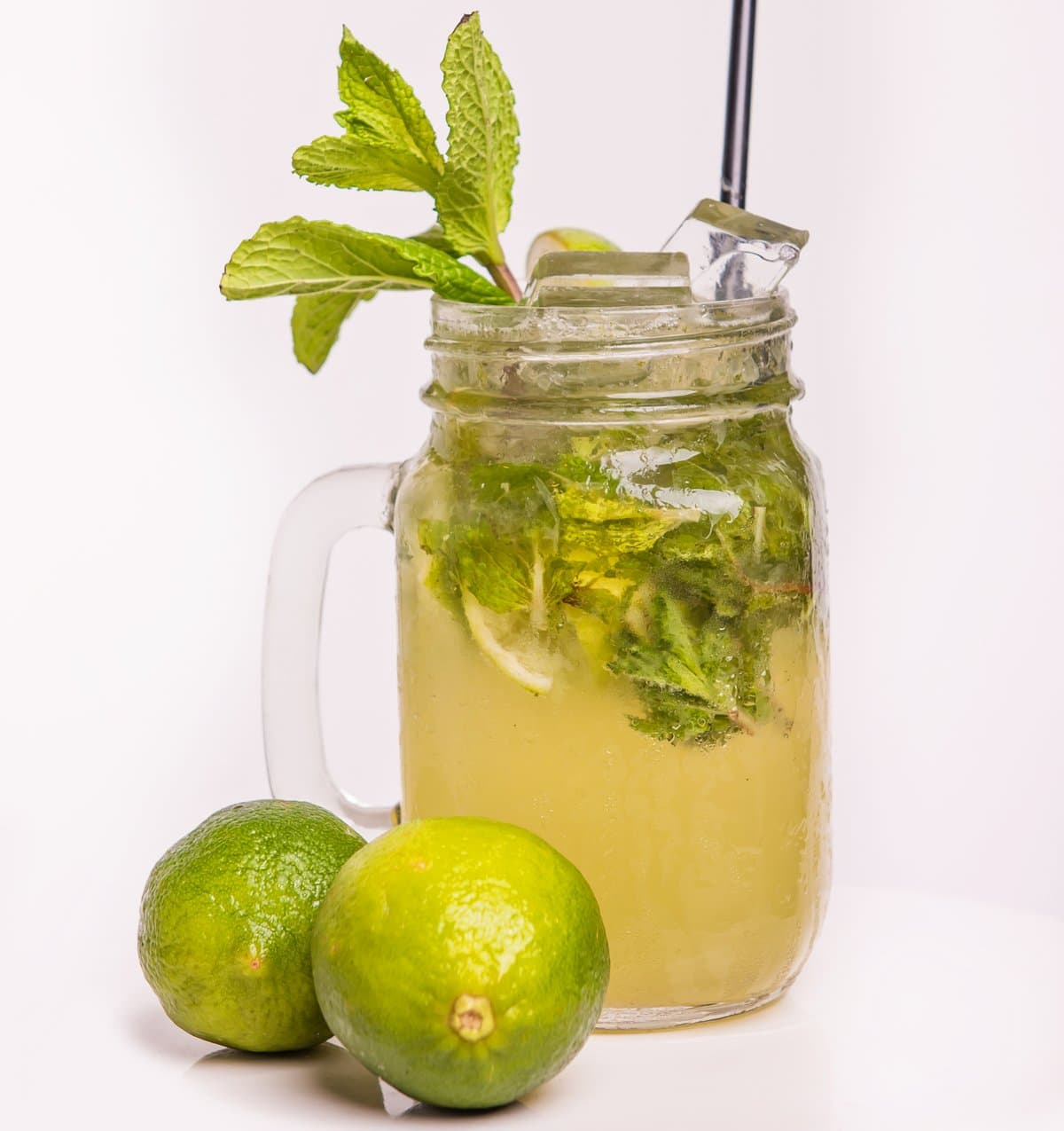 A mojito in a mason jar with mint and fresh limes