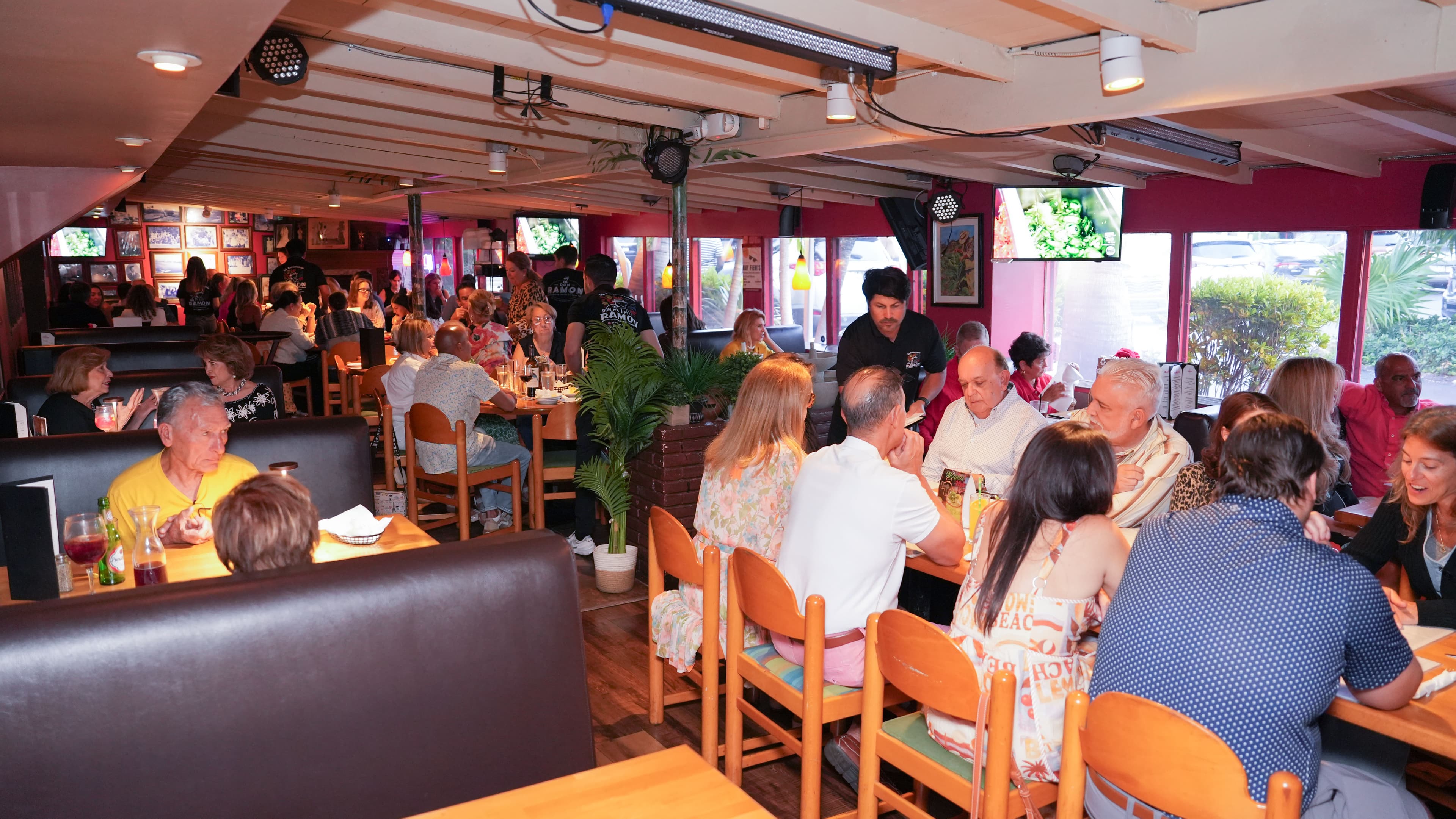 A busy lunch service seen down the length of the dining room, booths and tables full